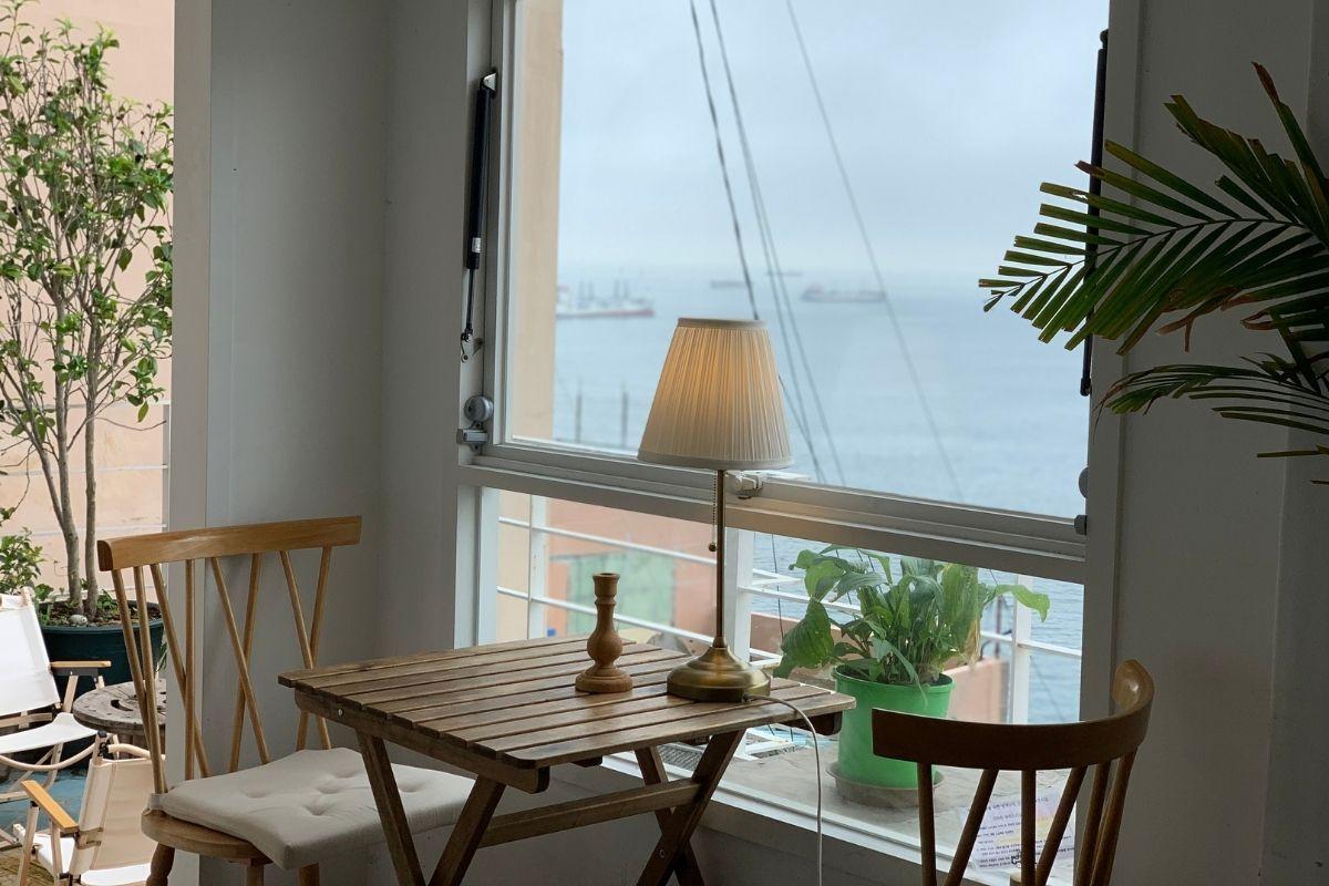 白淺灘文化村咖啡館的窗邊休閒區，木製小桌和椅子，可享受海景，感受悠閒的氛圍。