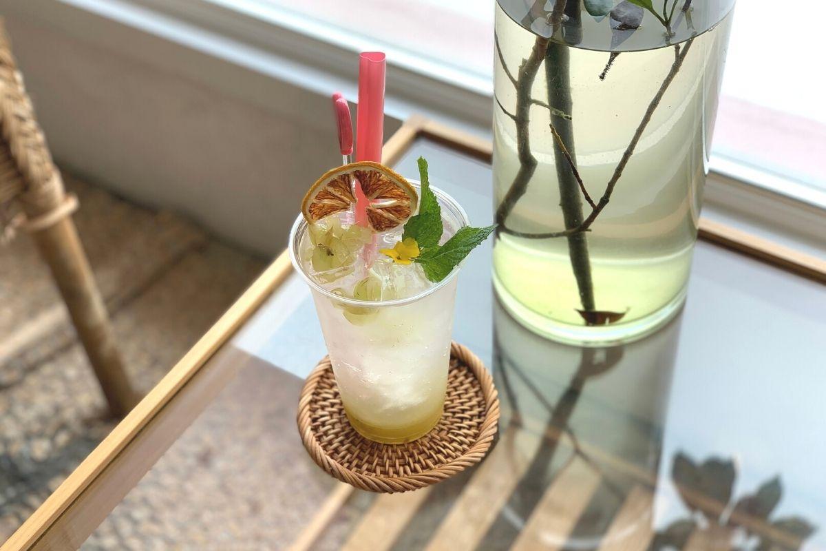 白淺灘文化村咖啡館的一杯檸檬飲品，附有薄荷裝飾，置於玻璃桌上，顯示清爽的夏季飲品選擇。