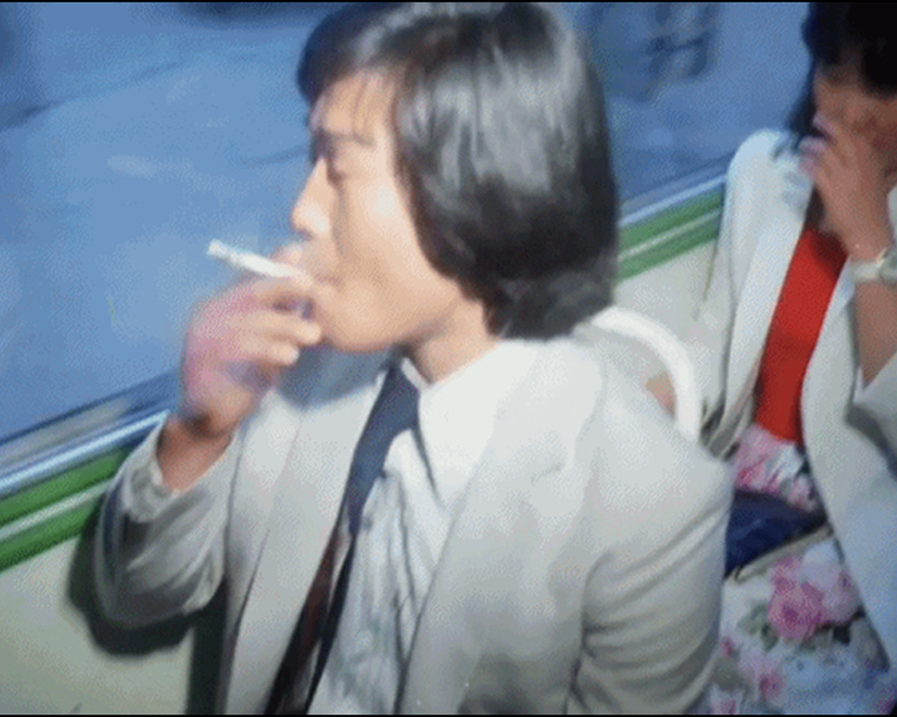 Korean man with long hair in a suit smoking on the bus in the 90s