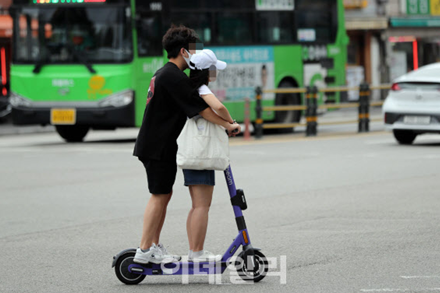 電動滑板車的兩人騎行，討論韓國法律對電動滑板車超載的罰則影響。