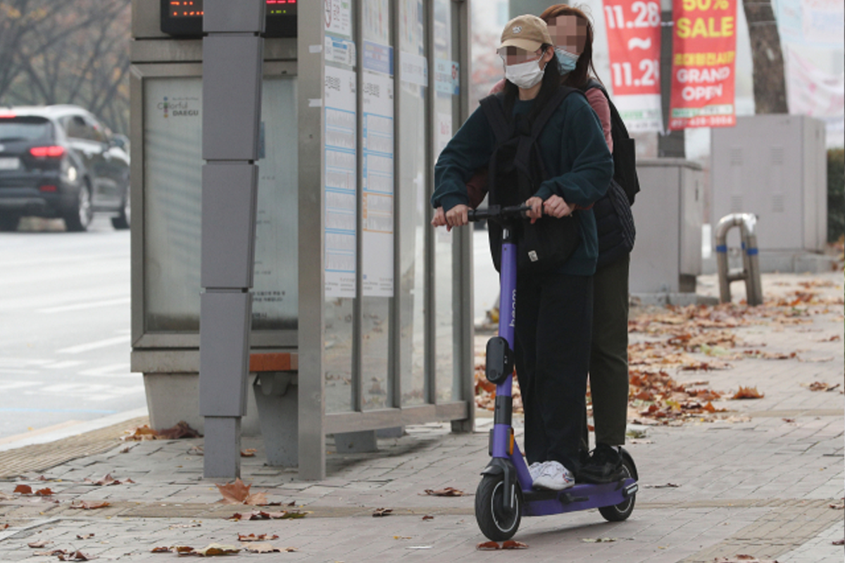 friends sharing an electric scooter together on the streets of Seoul