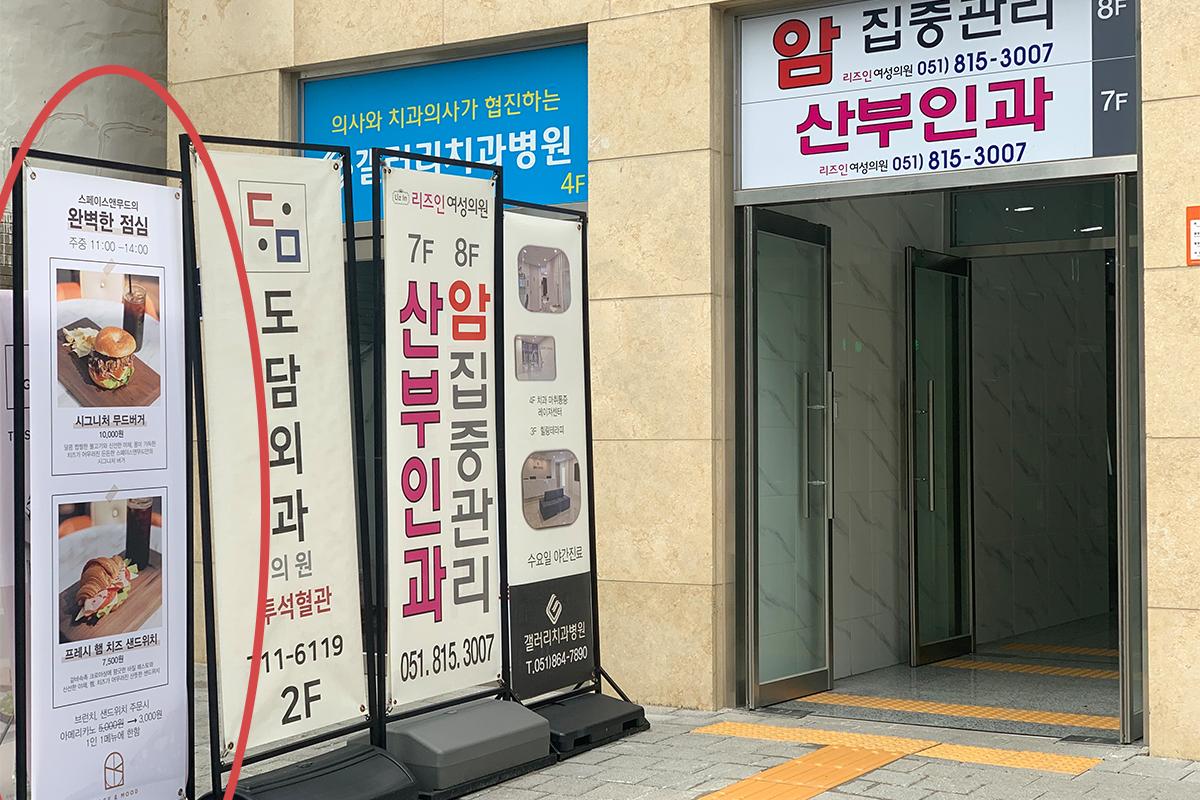 配有多個宣傳橫幅的建築入口，展示Space&Mood咖啡廳的午餐菜單。