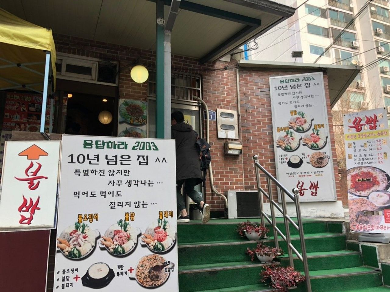 梨大불밥入口，展示多種韓式食物的廣告牌，吸引食客前來品嚐