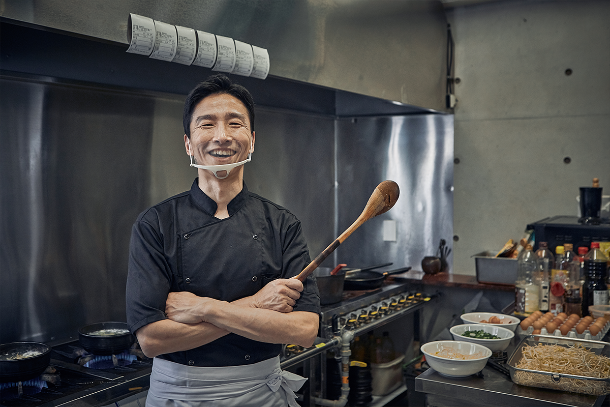 Korean chef in his kitchen posing with a big smile
