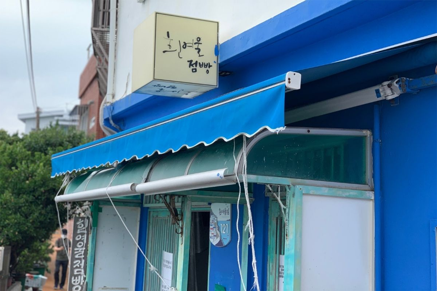 흰여울점빵의 간판과 푸르른 하늘과 어우러진 평화로운 이미지