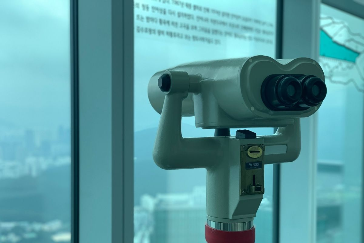 高空觀景台的觀景望遠鏡，讓遊客可以詳細觀察釜山的美麗風景，背景是模糊的城市天際線。