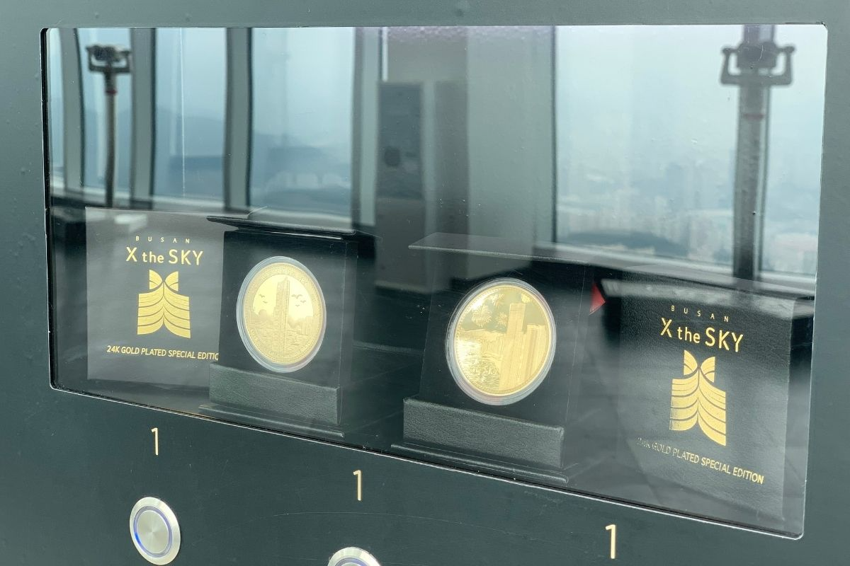 展示櫃中陳列的高級金幣紀念品，標有「24K鍍金特別版」，這些獨特的紀念品吸引著希望留念釜山的遊客。