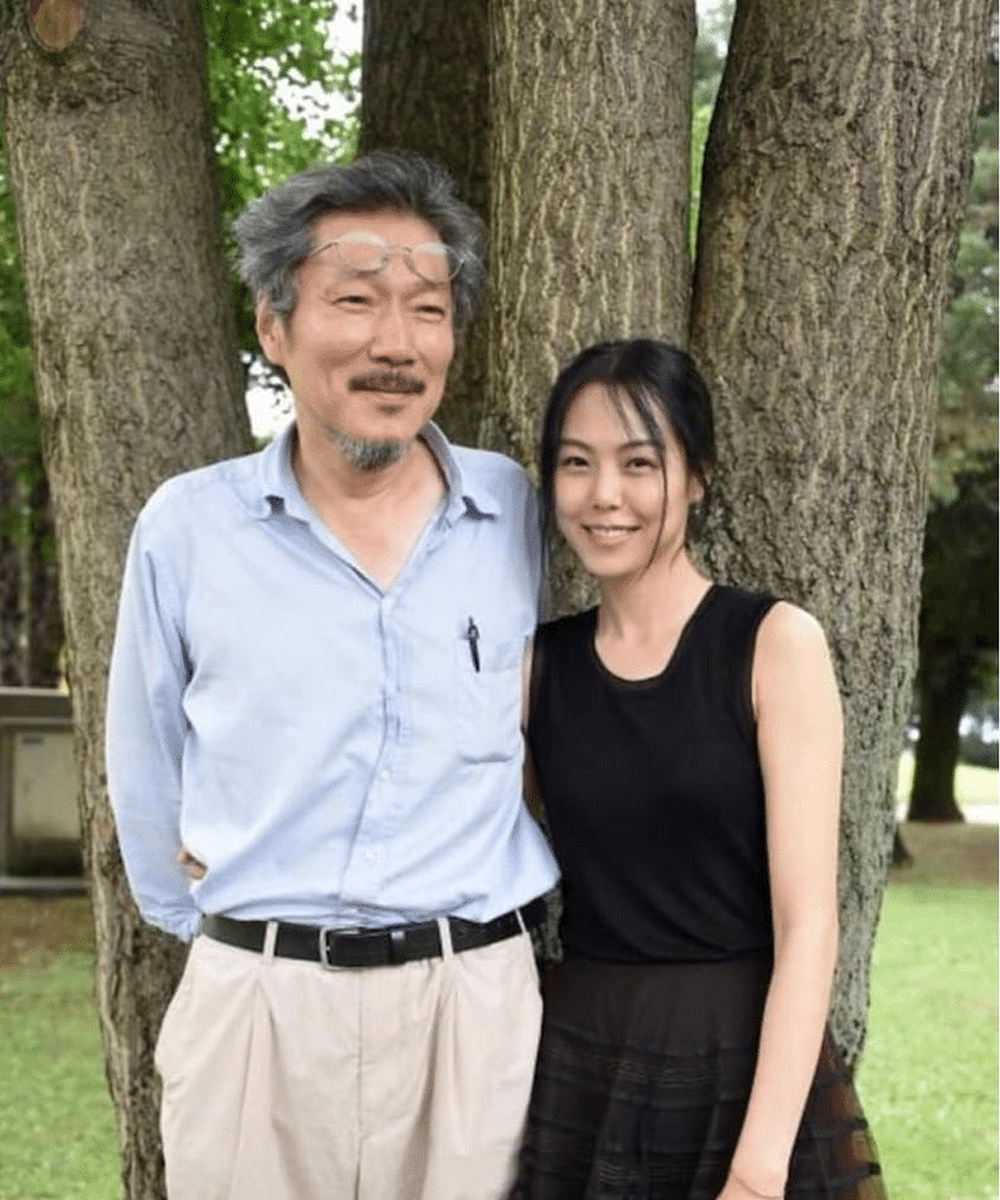 有名監督と女優のペア、カジュアルなブルーシャツとチノパンスタイル。