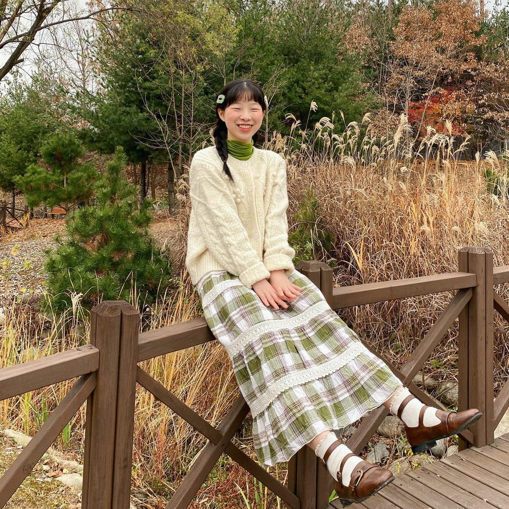自然の中で楽しむ、カントリースタイルのアイボリーニットとチェック柄スカート。