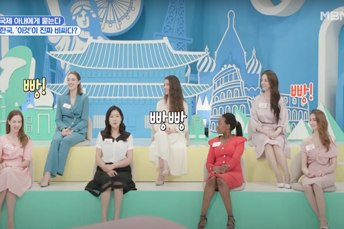 韓國綜藝節目中的一幕，多名穿著正式服裝的嘉賓坐在彩色階梯上，背景是充滿韓國建築風景的畫面，螢幕上顯示字樣'빵빵'。