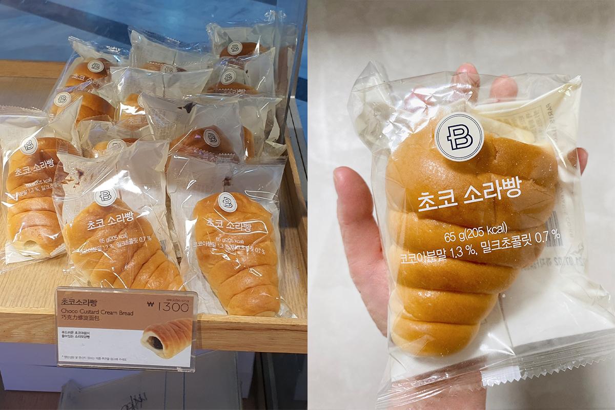 韓國某麵包店的展示櫃中，包裝好的巧克力卡士達麵包，價格標示為1300韓元，小麵包放在板子上，展示出了不同角度的包裝樣本。