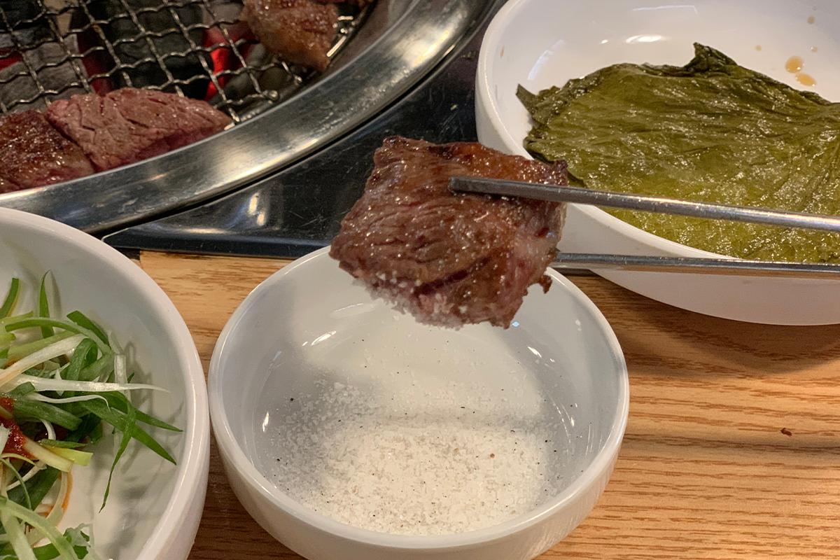 用筷子夾取韓牛肉塊沾鹽，充分品味其鮮美。