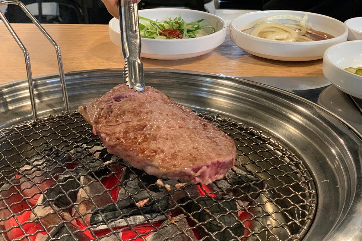 韓牛肉在炭火上被烤得外焦裡嫩，呈現誘人的顏色。
