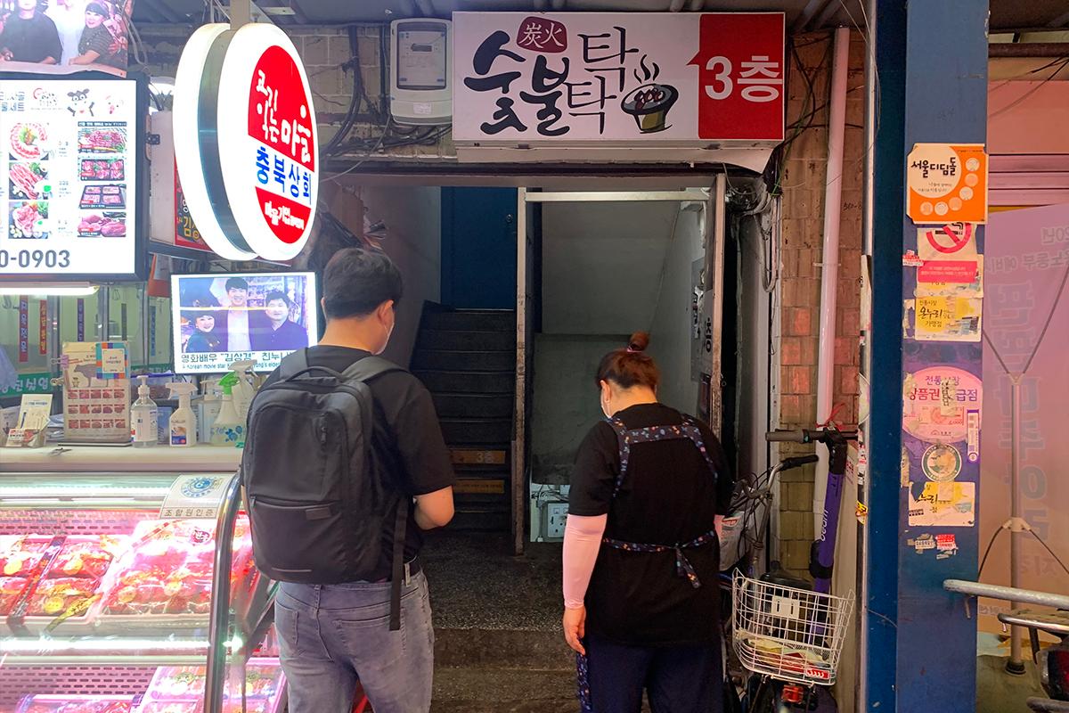 兩位顧客正準備上樓進入華新畜產合作的炭火燒烤餐廳。