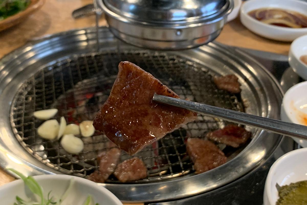 筷子夾起一塊剛烤好的韓牛肉，將其送入口中。