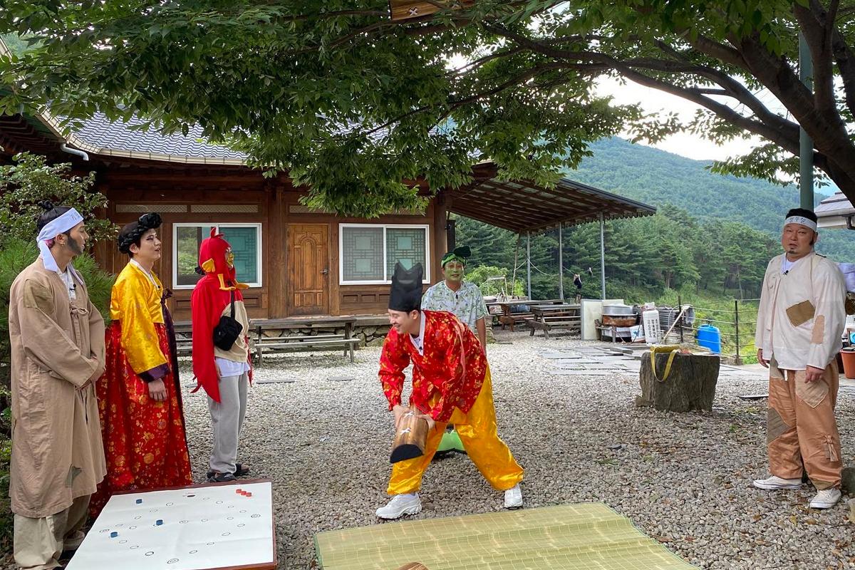 由韓綜新西遊記8主題節目拍攝的場景，參與者穿著韓國傳統服飾並擺出具代表性的韓劇姿勢，背景顯示韓國的鄉村風景。