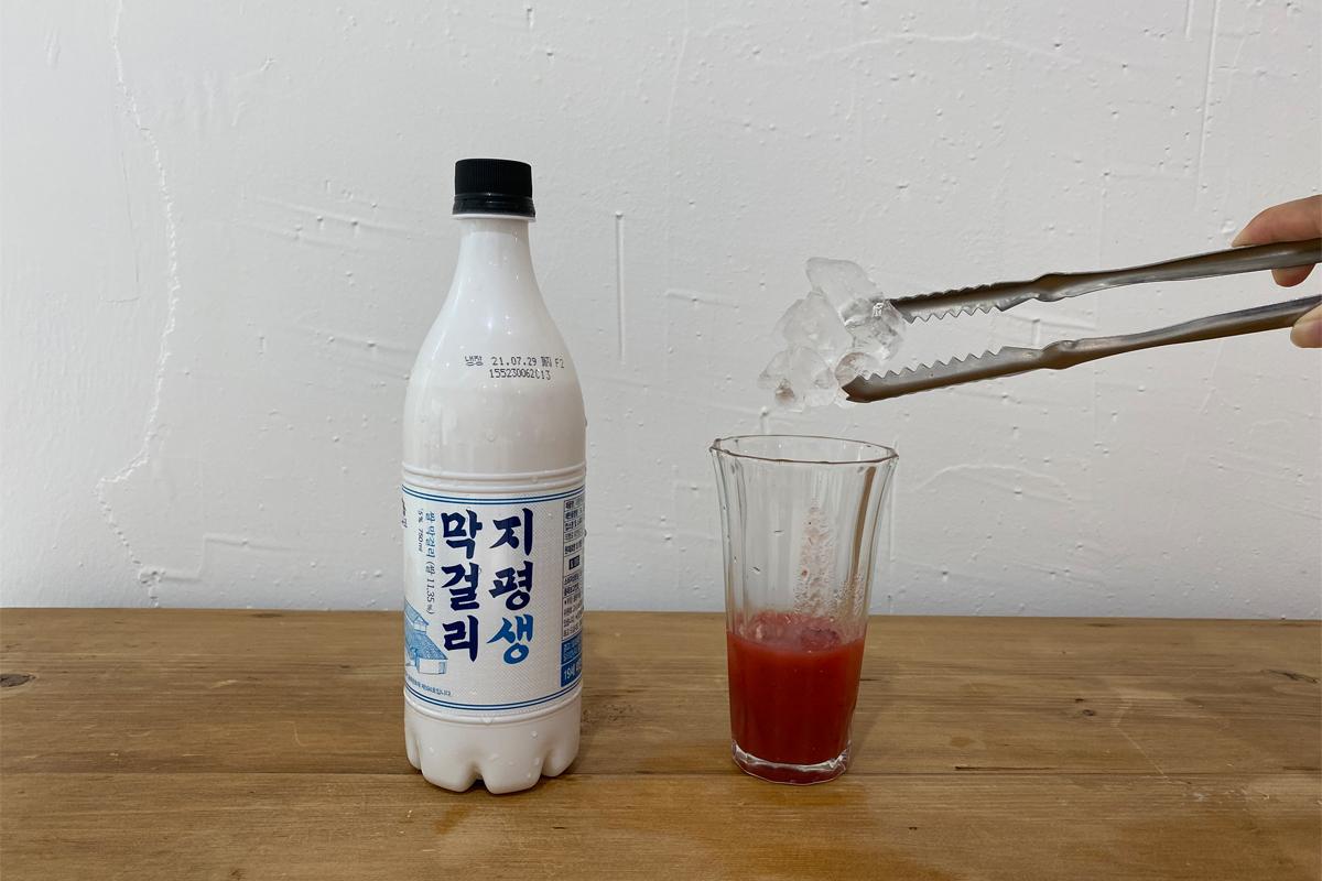 Adding ice to to cup with strawberry juice