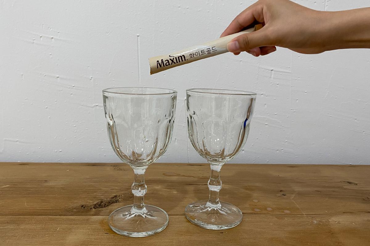 Pouring coffee mix into one of two glasses on table