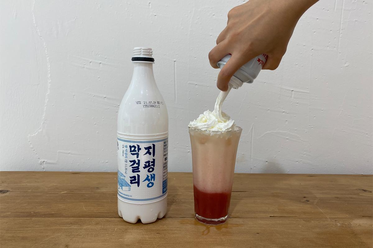 Adding whipped cream to top of strawberry cocktail