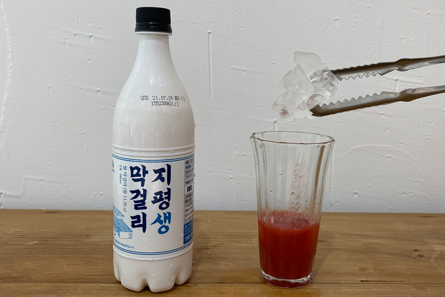 在玻璃杯中加入草莓汁和冰塊，為草莓米酒調酒打下基礎。