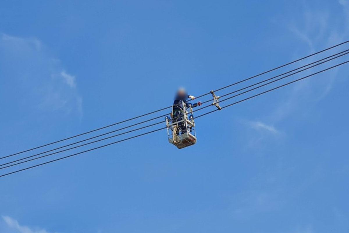 ช่างไฟฟ้ากำลังทำงานบนสายไฟแรงสูงในเกาหลีใต้บนกระเช้ารอกเหนือพื้นดิน