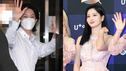 背景にガラスの壁面がある整理されたイベント会場で手を振る白いシャツを着た人物と、レースのドレスを着た人物。