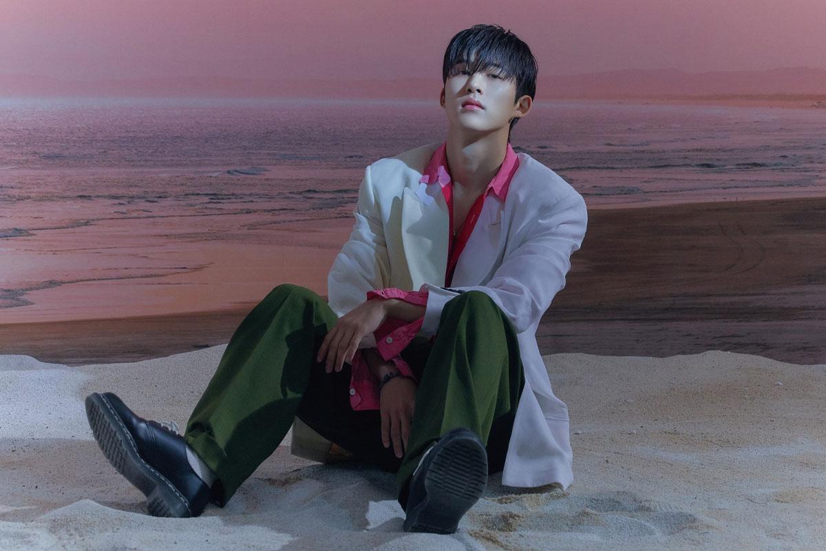 ภาพไอดอลเกาหลี B.I. ในเสื้อเชิ้ตสีขาวและเสื้อคลุมสีขาว ในสถานที่ริมทะเล ภาพนี้ใช้สำหรับข่าวการพิจารณาคดีของ B.I.