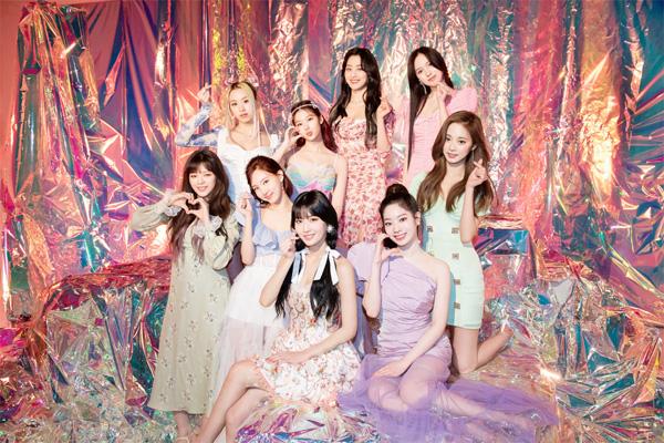 カラフルな背景に座った韓国のガールズグループTWICEのメンバーたちの集合写真。ビルボード200チャートで新記録を達成しました。