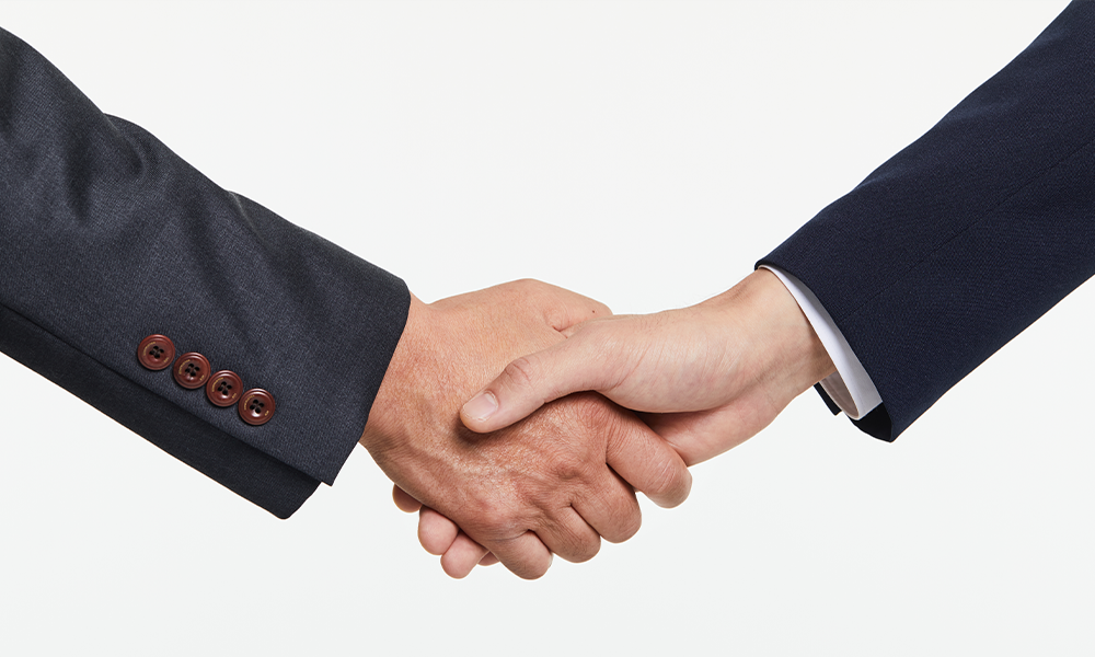 two men in suits giving eachother a handshake