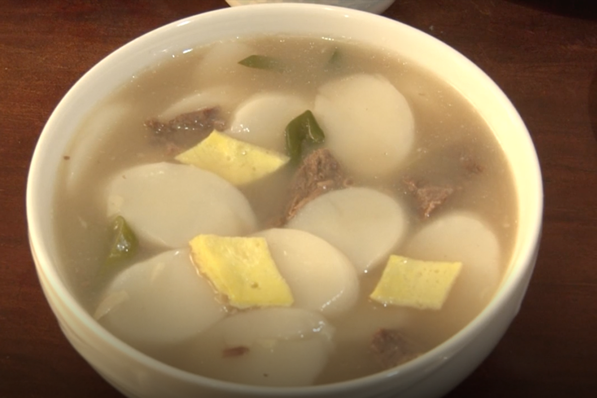 一碗韓國年糕湯，上面飄著幾片年糕、韓牛肉塊以及蔬菜，適合於農曆新年食用的傳統美食，象徵著慶祝與潔淨。