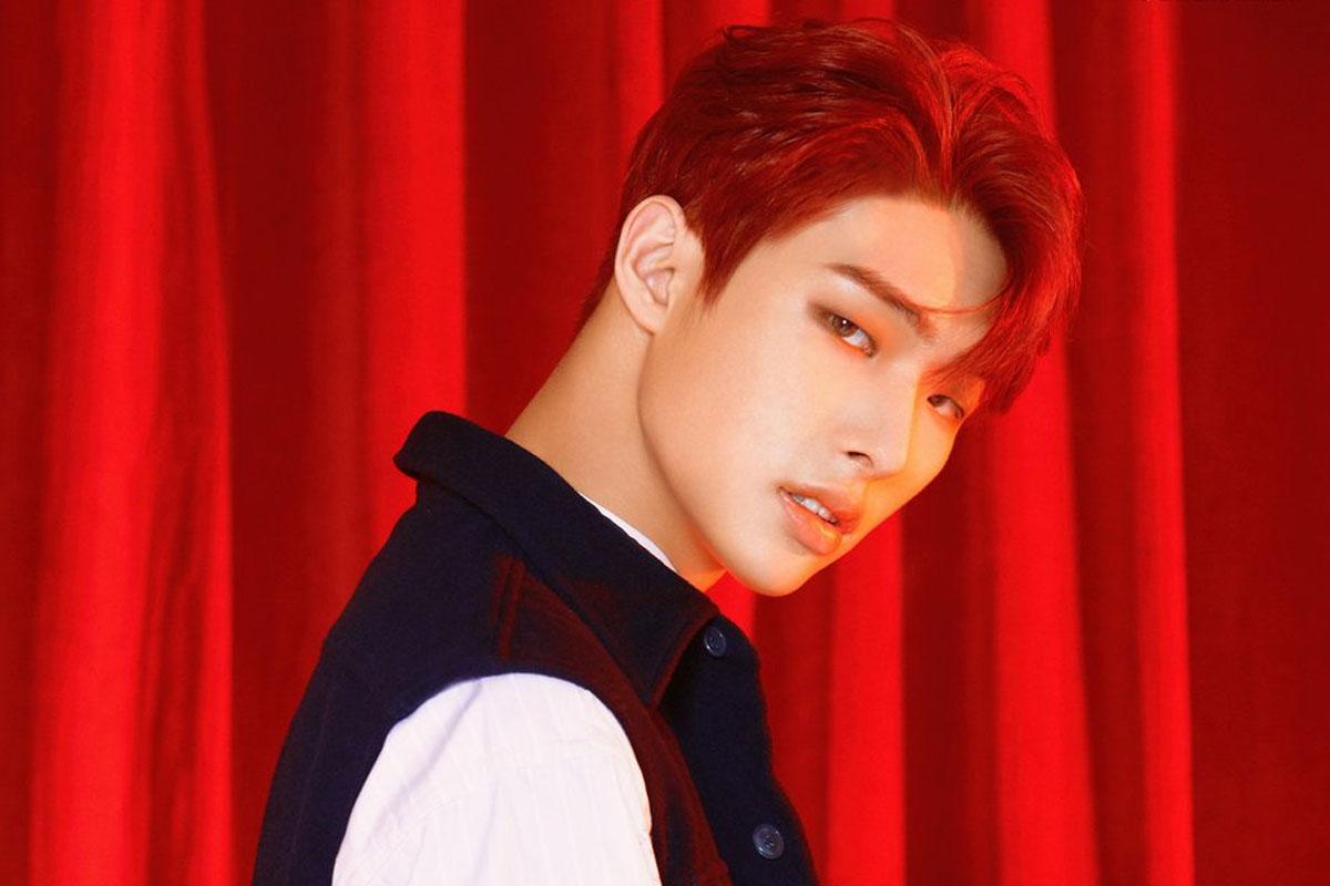 มินกิจาก ATEEZ ในเสื้อแจ็กเก็ตสีแดงพื้นหลังม่านสีแดง