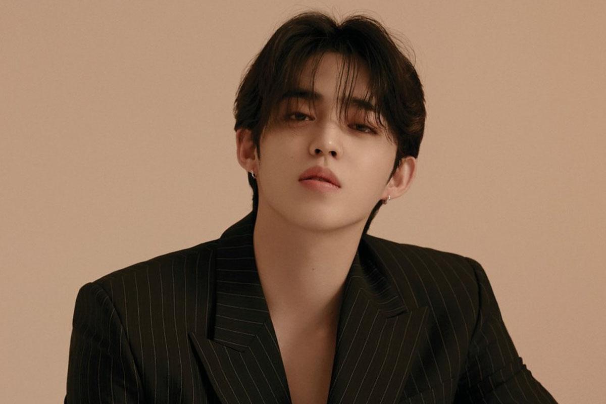 S.coups จาก SEVENTEEN ในชุดสูทสีดำลายทางและพื้นหลังสีเบจ