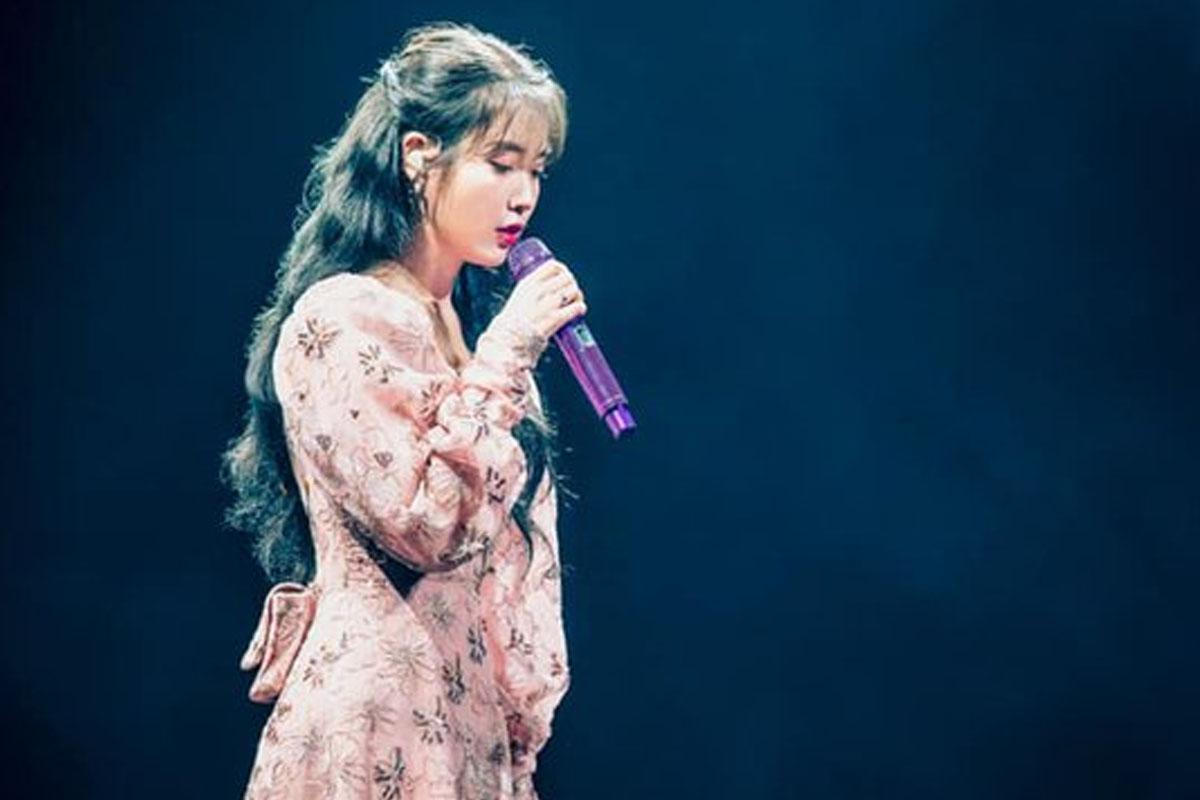 นักร้องหญิงสวมชุดเดรสสีชมพูในคอนเสิร์ตแสดงสดกลางเวที