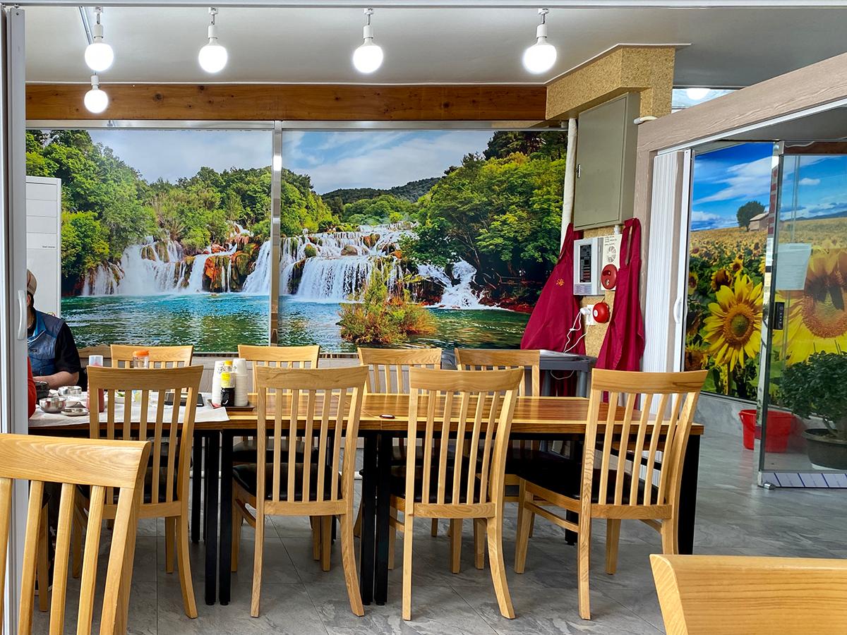 Light wooden chairs with a huge wall showing waterfalls at a restaurant in Busan