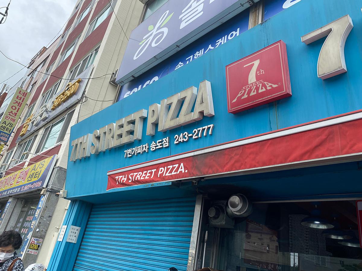 Street view of 7th Street Pizza restaurant entrance in Busan, South Korea.
