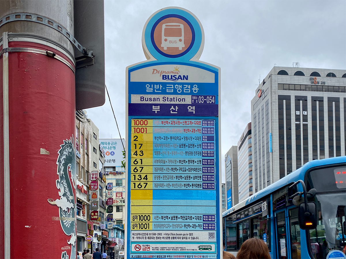 Busan Station bus stop sign indicating various bus routes and schedules.
