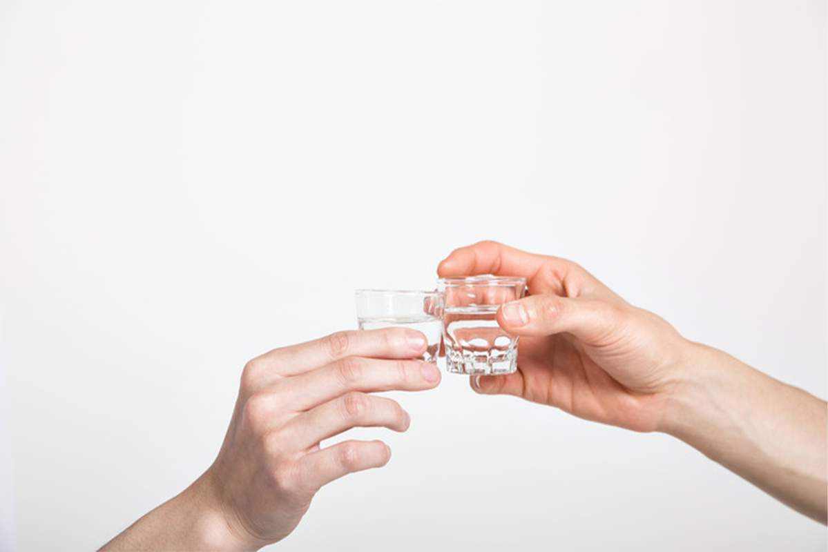 兩隻手拿著酒杯，展示韓國燒酒文化中的乾杯習俗及燒酒杯的設計。