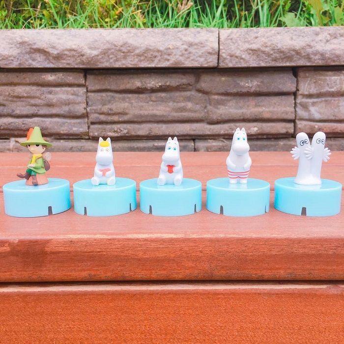A lineup of Moomin figurines on blue bottle caps showcasing collectible items at GS25 convenience store