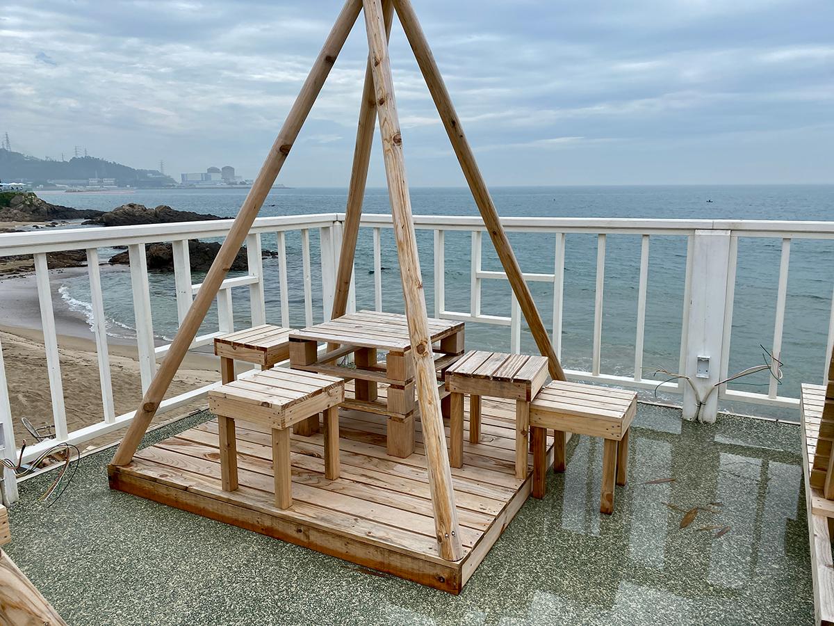 A wooden table with stools on the balcony of Haeundae Haemul Kalguksu in Gijang, Busan