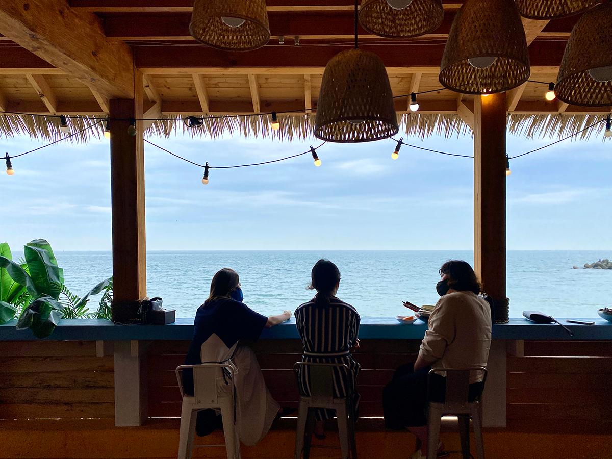 Silhouettes of three ladies talking on the bar table while looking towards the ocean, Busan