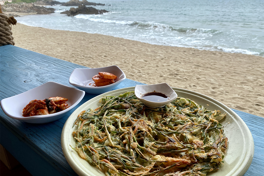 使用剪刀切割青陽辣椒韭菜煎餅，呈現韓國傳統用餐方式。