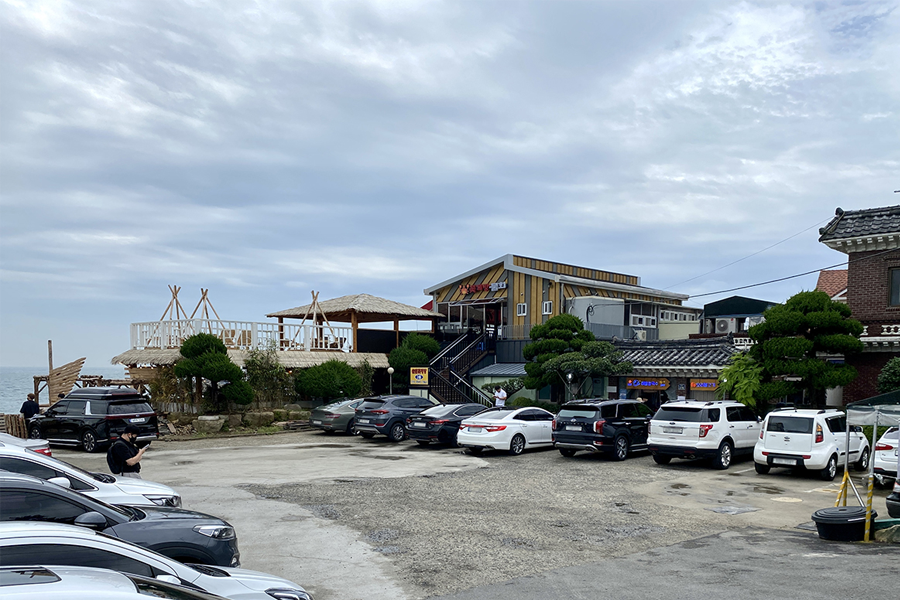 釜山機張的餐廳外部，顯示停車場幾乎停滿車輛，展示該餐廳受歡迎的程度。
