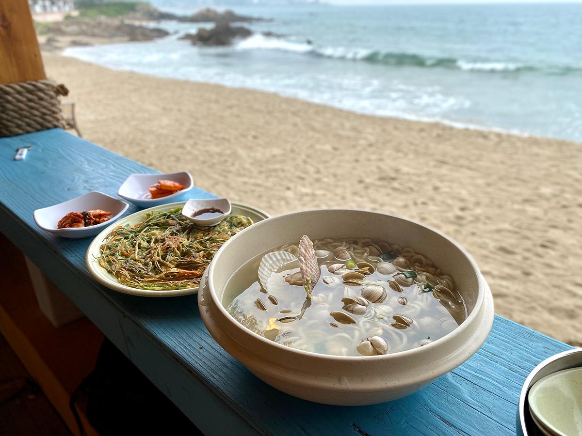 From back to front, two kimchi dishes, chive pancake and kalguksu (seafood noodles) in Gijang, Busan