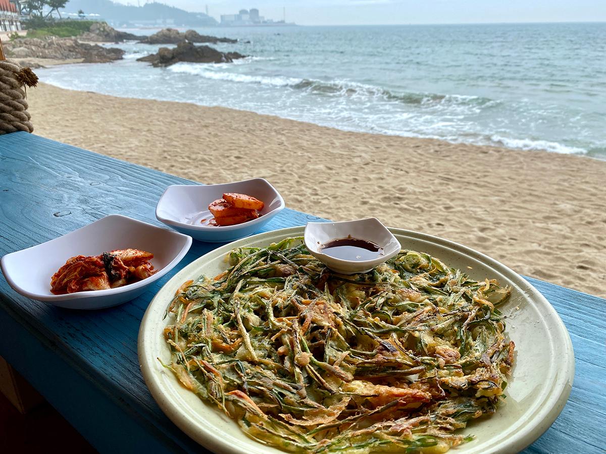 chive pancake and two kimchi dishes on the bright blue table in Busan