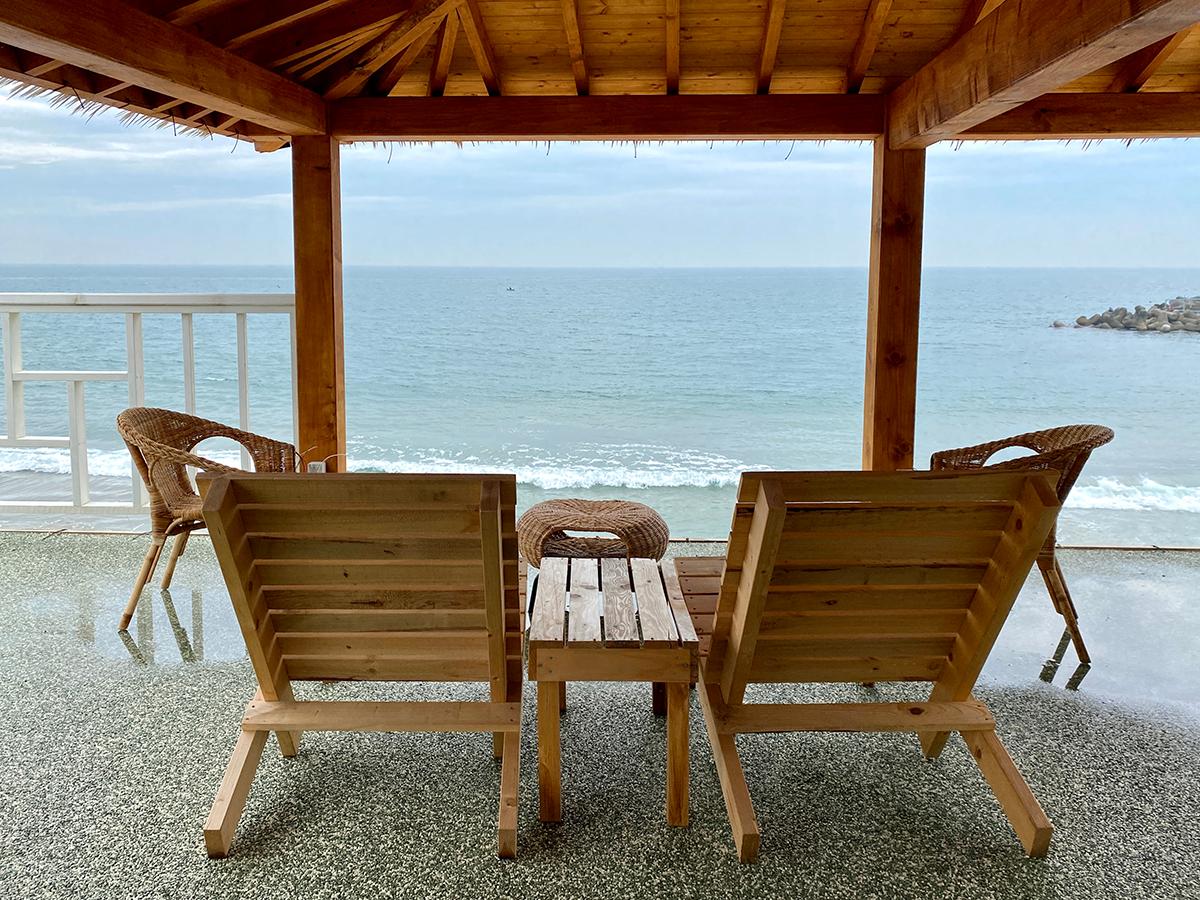 Wooden lounge chairs on the balcony of Haeundae Haemul Kalguksu looking towards the ocean waves