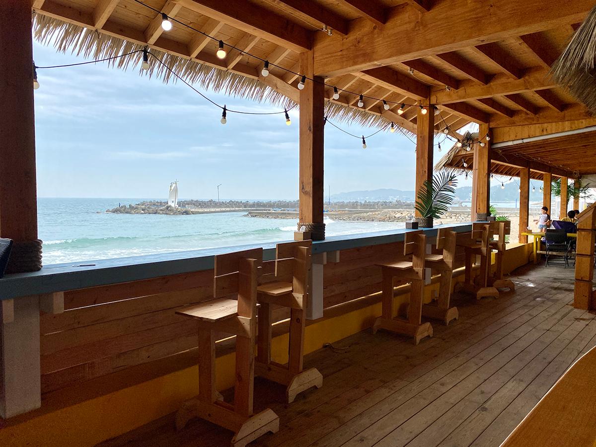 Wooden bar tables and chairs looking towards the blue ocean in Gijang, Busan