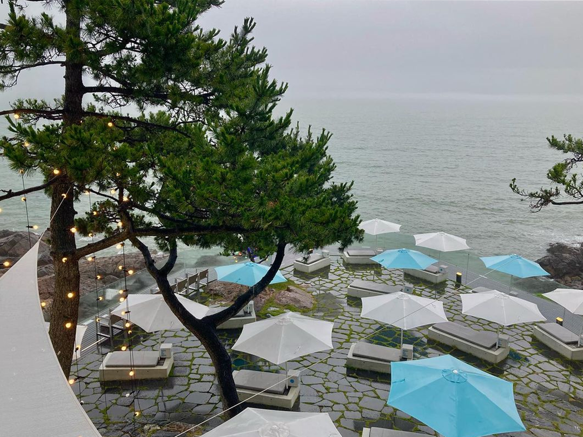 The oceanfront lounge area of Waveon Coffee with white and light blue parasols.