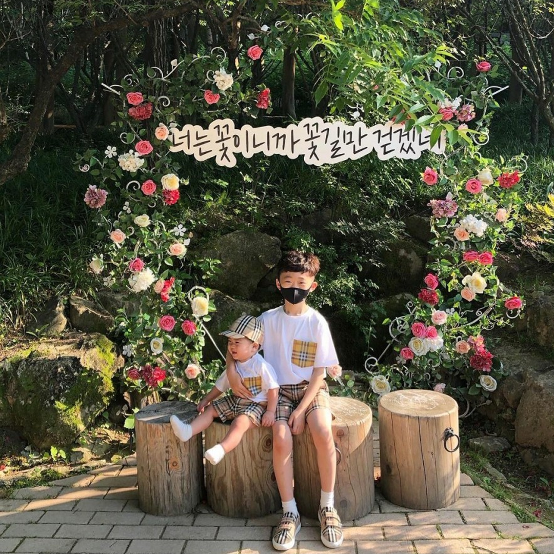 A boy and baby brother sitting in front of a large floral wreath