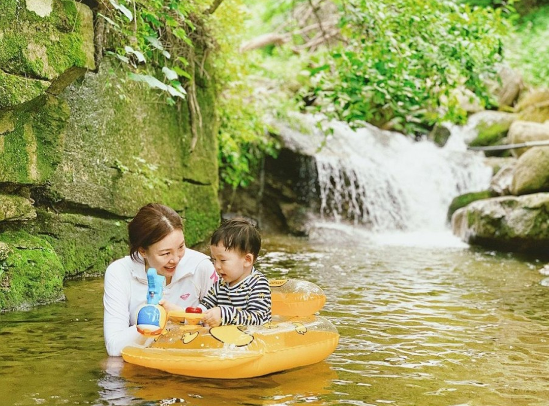 Toddler and mom play in the stream