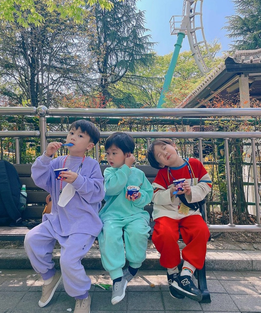 在E-World游乐园外休息的三个孩子，各自享用零食